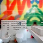 A vibrantly designed bathroom featuring colorful tiles, a bathtub, sink, and toilet.